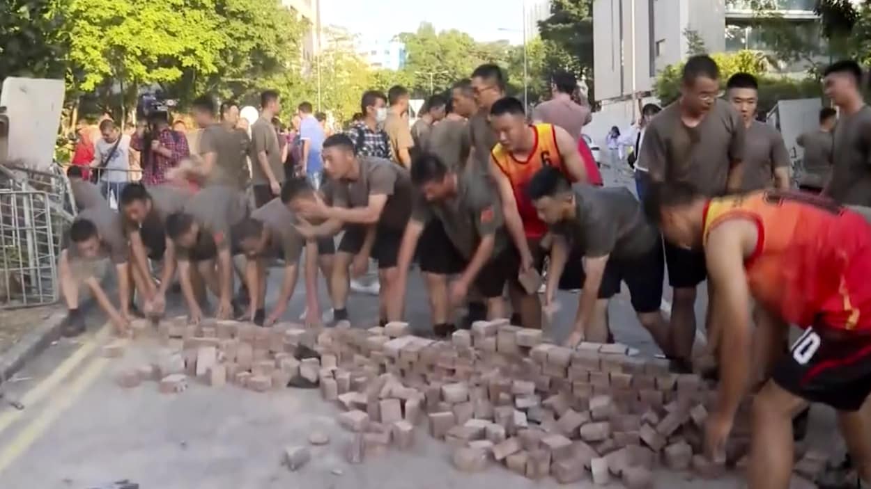 Une capture d’écran montre des soldats chinois, vêtus de shorts et de t-shirts, ramassant des briques dispersées par des manifestants à l'Université baptiste de Hong Kong, le samedi 16 novembre 2019.