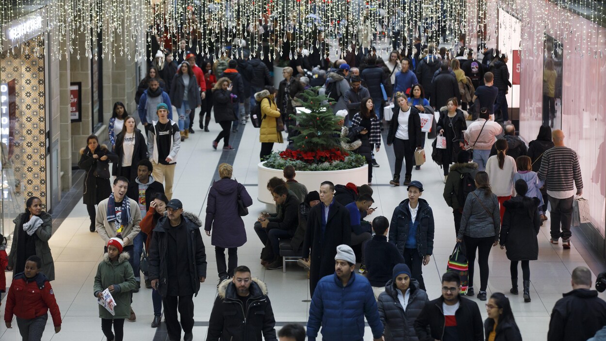 Une foule dans un centre commercial décoré pour Noël.