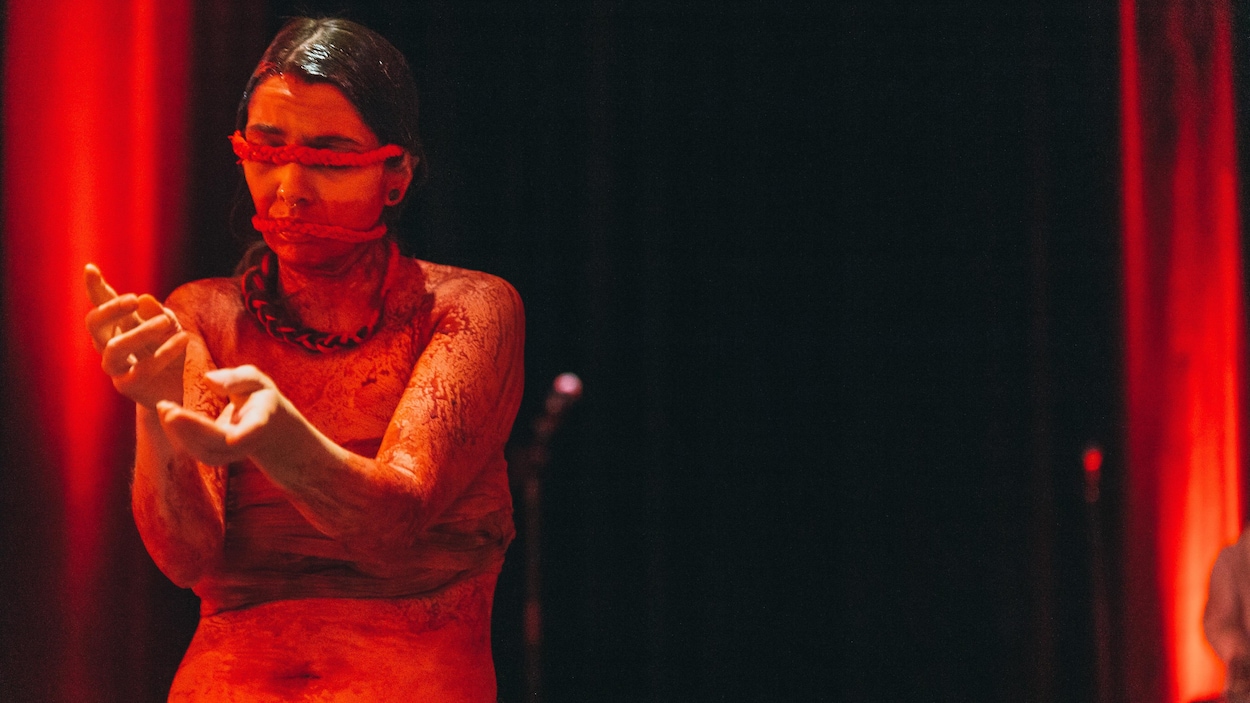 L'artiste a le corps enduit de peinture rouge. Une ficelle rouge bande ses yeux et sa bouche.