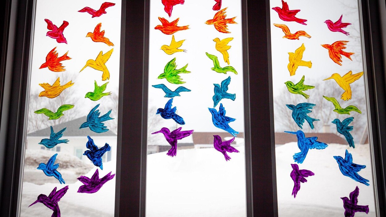 Une fenêtre avec des oiseaux peints aux couleurs de l'arc-enciel