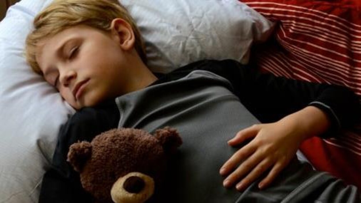 Un garçon d'environ 12 ans qui dort avec un ourson en peluche. Un garçon d'environ 12 ans qui dort avec un ourson en peluche.