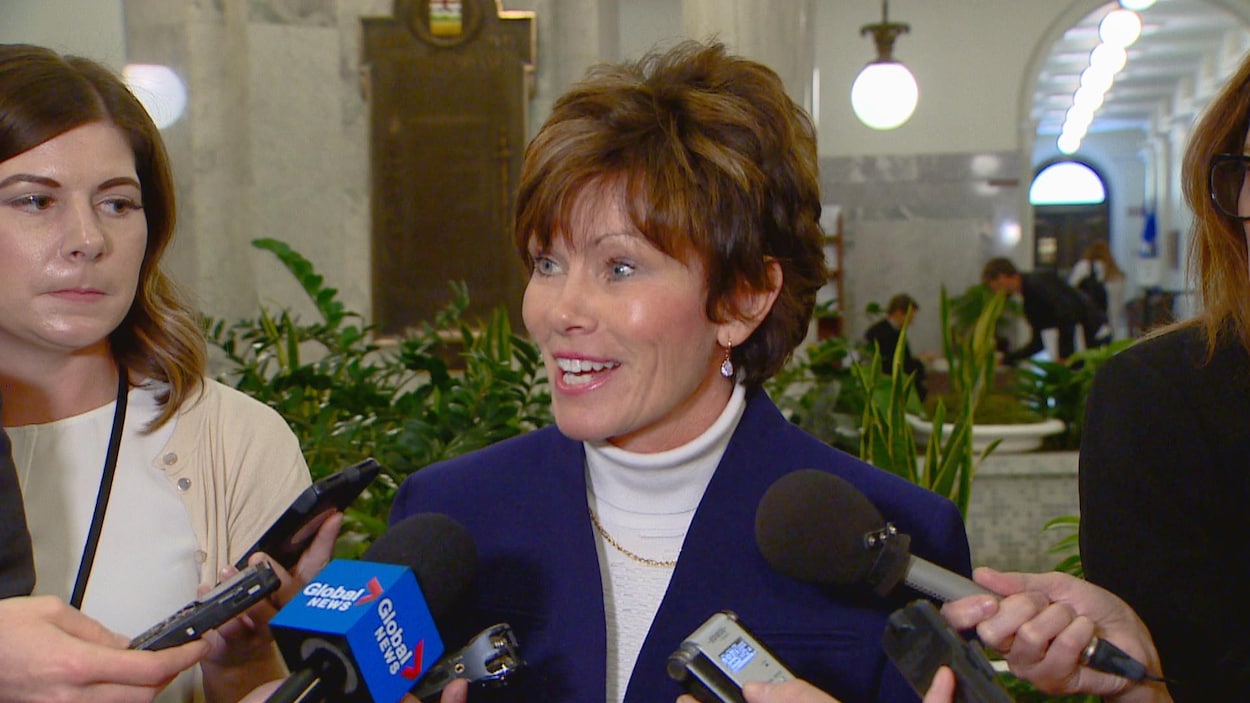 Sonya Savage en mêlée de presse dans les couloirs de la législature. Elle sourit.