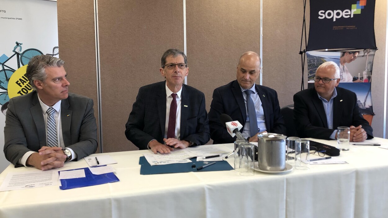 Quatre hommes assis à une table pendant un point de presse.