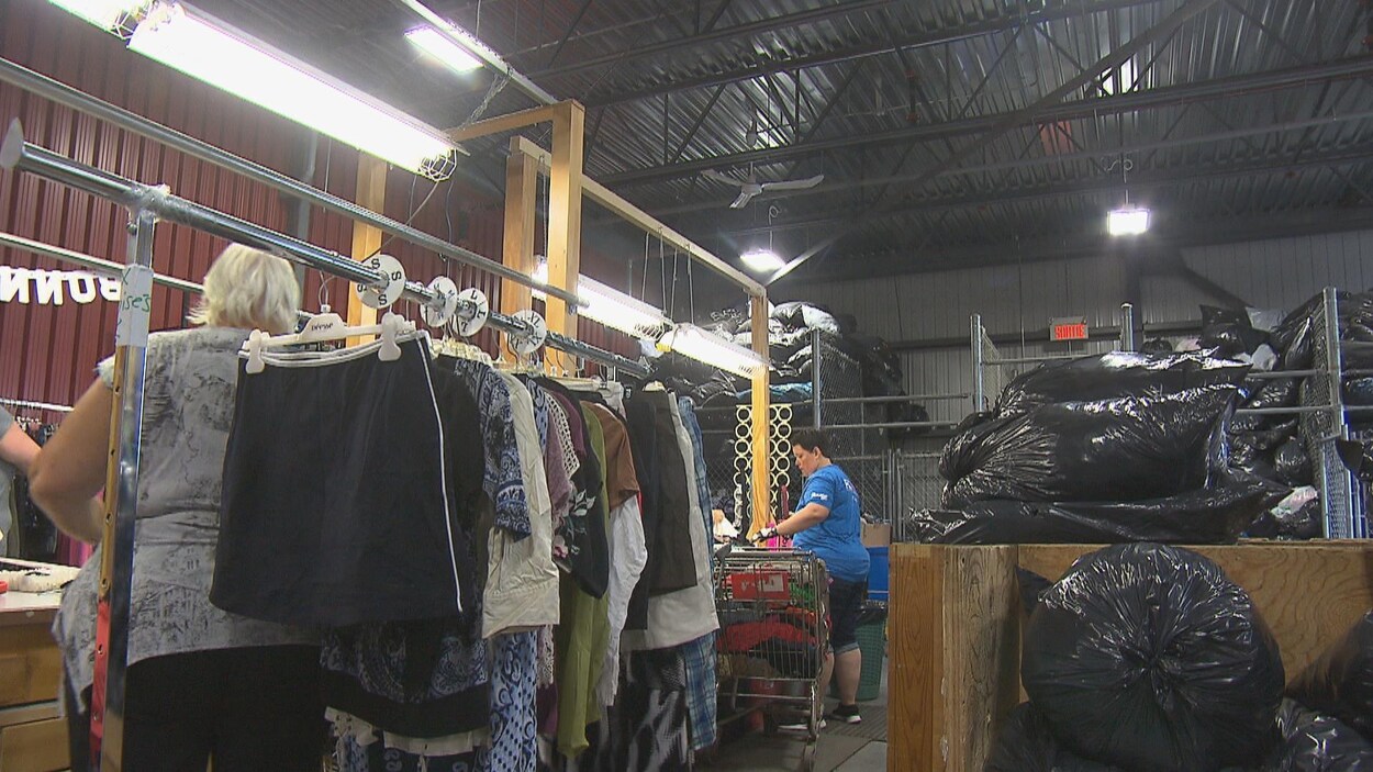 Des employés qui trient des vêtements et de la marchandise de toutes sortes dans un entrepôt.