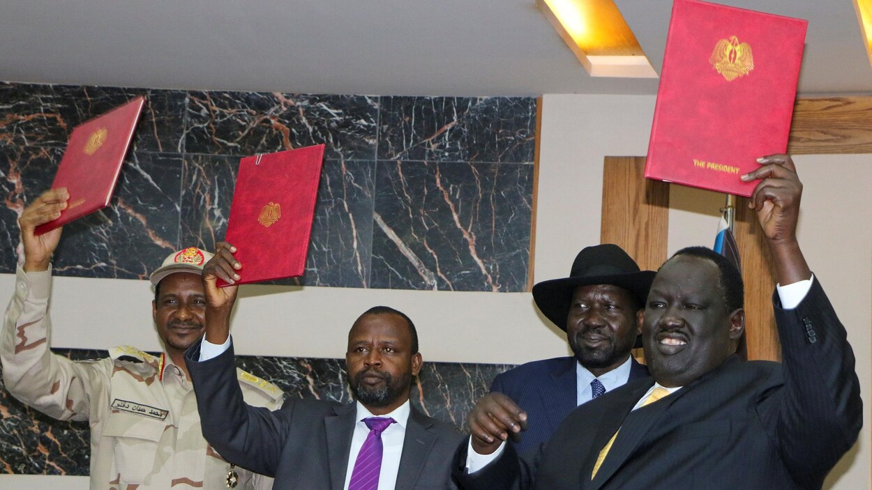 Quatre hommes portent un document dans leurs mains.