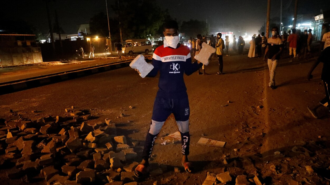 Un manifestant masqué brandit deux pavés.