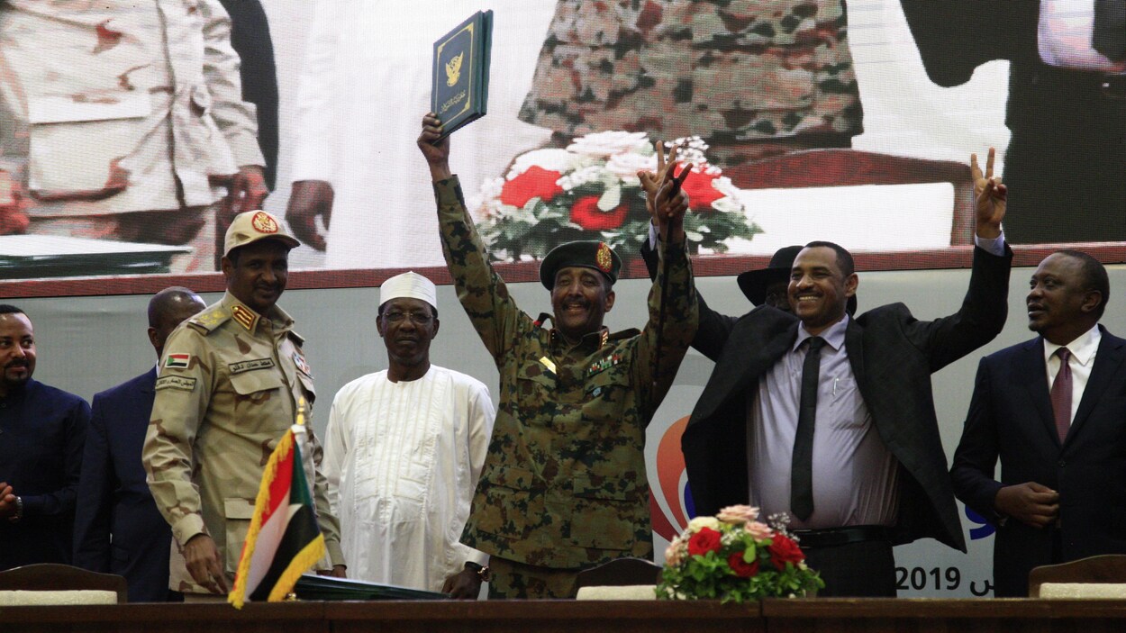 Le chef du conseil militaire de transition, le général Abdel Fattah al-Burhan, et le chef de la coalition de l'opposition, Ahmad Rabie, lèvent les bras après avoir signé la déclaration constitutionnelle.