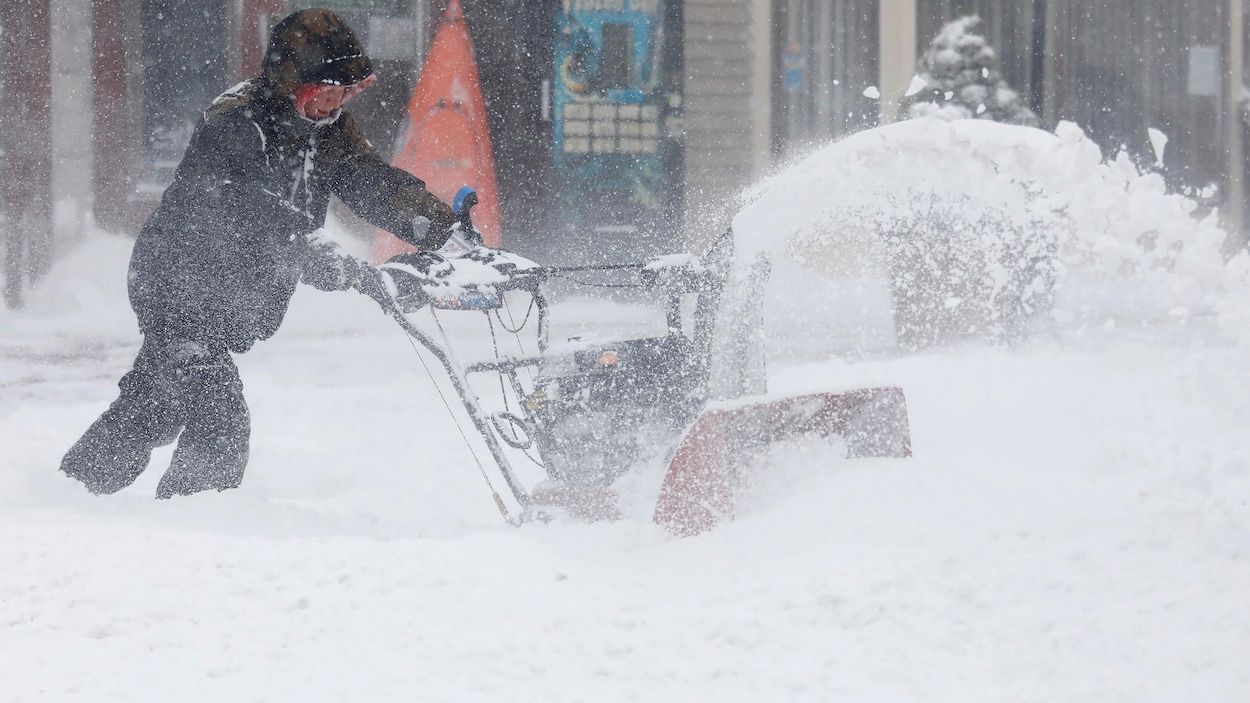 Un homme utilise une souffleuse à neige à Port Washington à New York.
