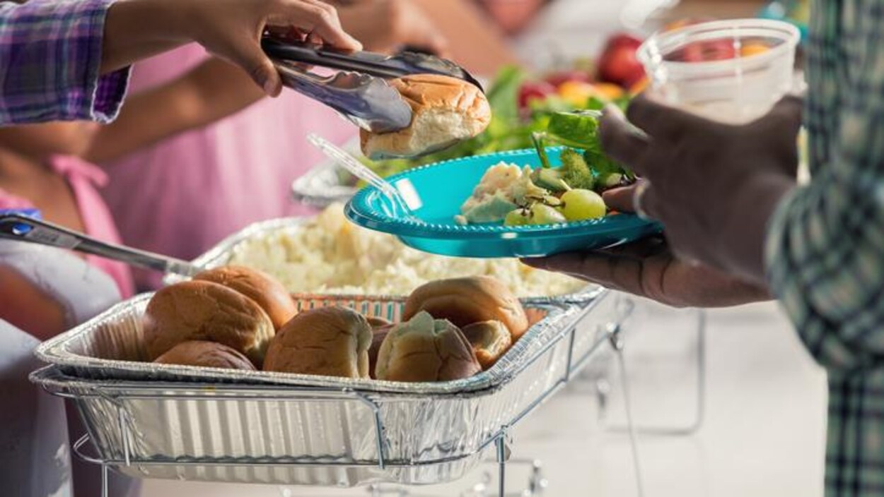 Deux personnes dont l'une a une assiette remplie de nourriture. Deux personnes dont l'une a une assiette remplie de nourriture.