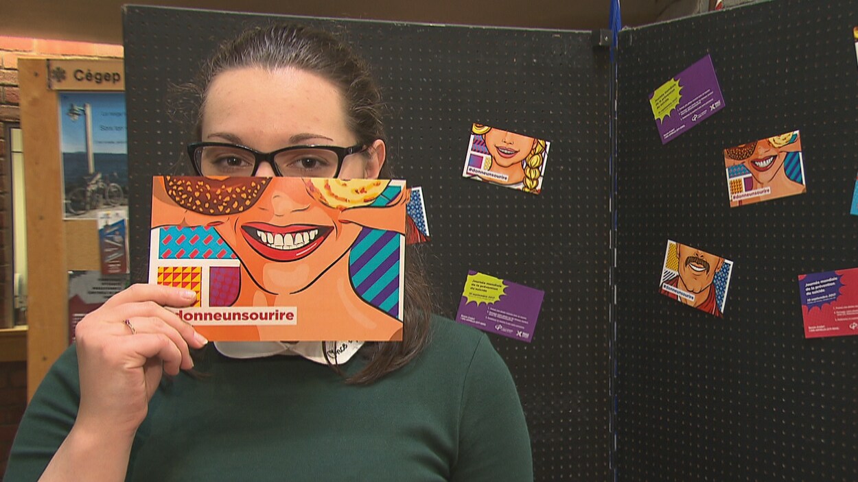Une jeune femme tient un carton avec un sourire dessiné dessus devant son visage. Une jeune femme tient un carton avec un sourire dessiné dessus devant son visage.