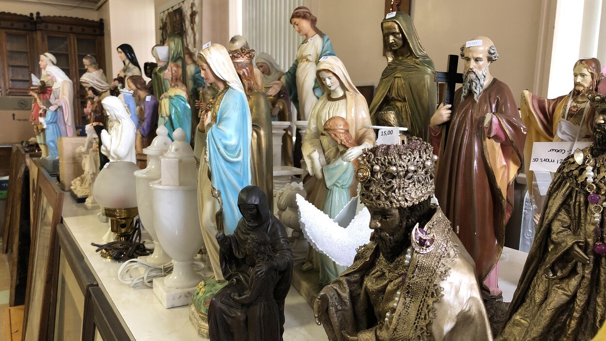 Une série de figurines chrétiennes sont disposées en rangée sur une table. 