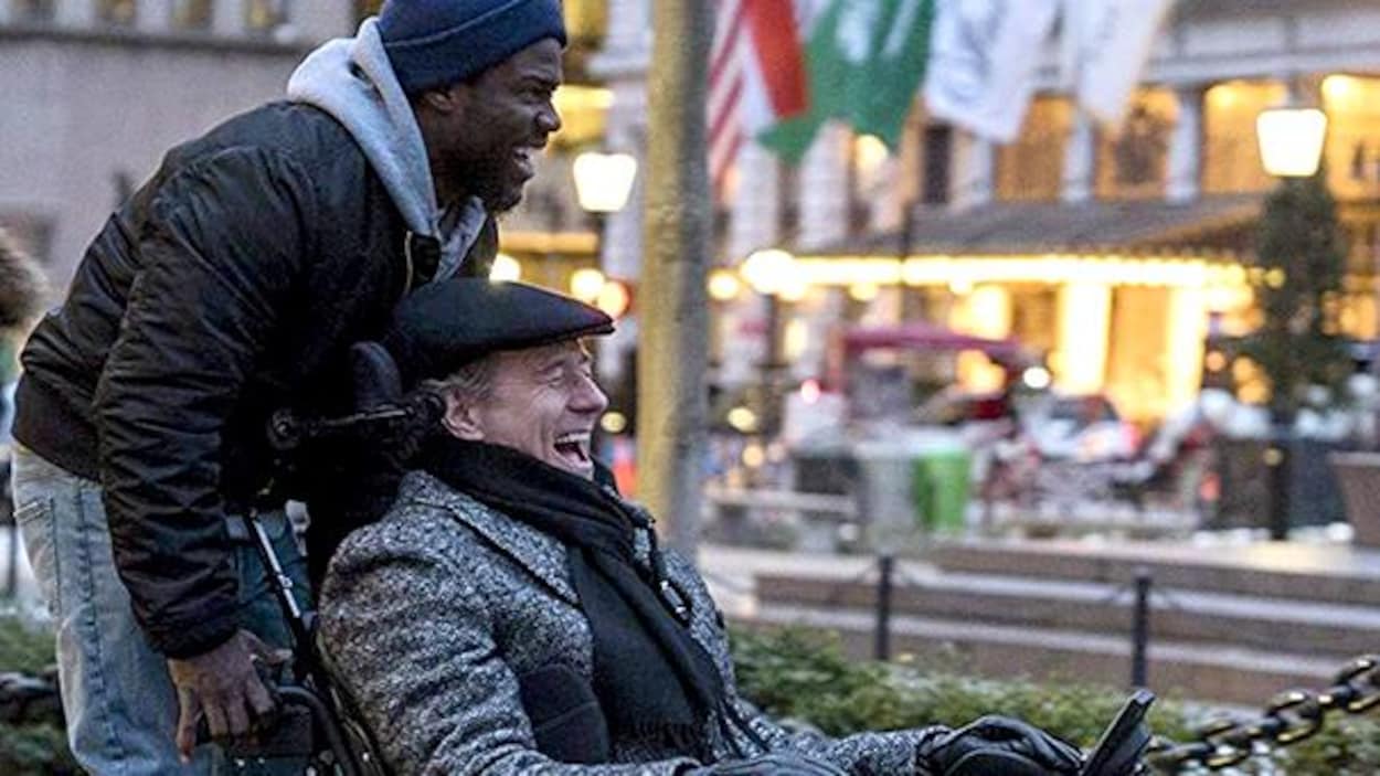 Un homme pousse un autre homme dans un fauteuil roulant et ils rient.