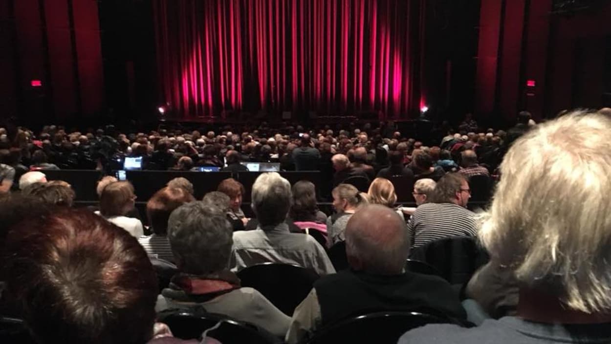 Le public assis, attend l'ouverture du rideau de scène.