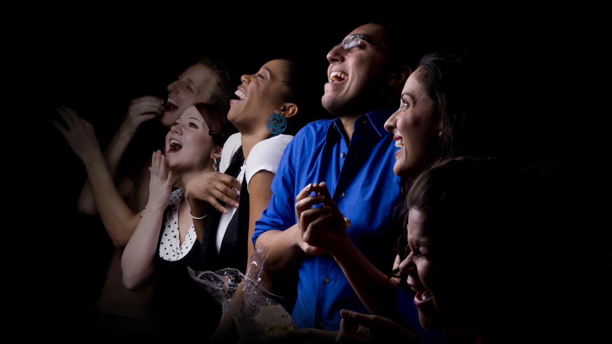 Plusieurs personnes rient en regardant un spectacle.