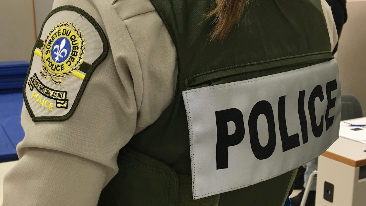 Inscription du mot police sur le dos d'une uniforme que porte une policière de la Sûreté du Québec