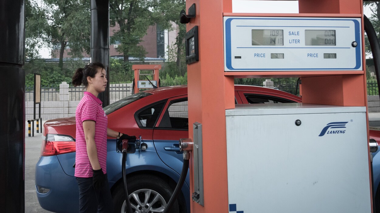 Une Nord-Coréenne met de l'essence dans une voiture. Une Nord-Coréenne met de l'essence dans une voiture.