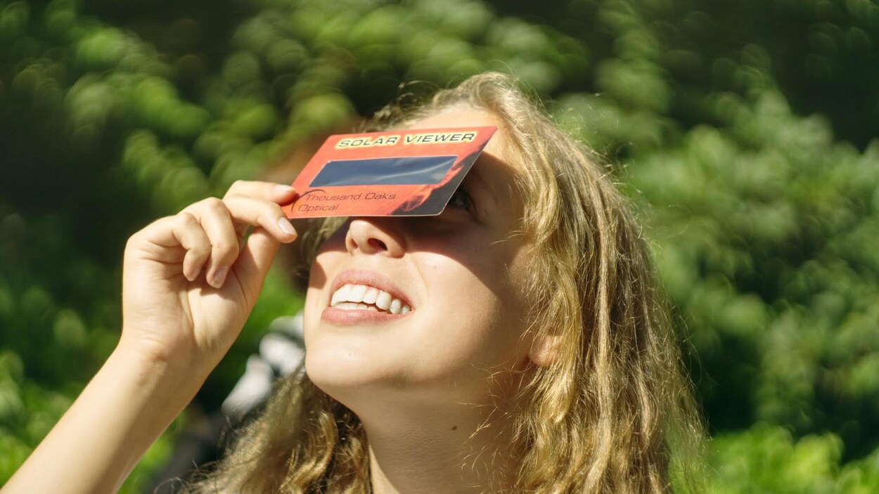 Une adolescente observe une éclipse avec des lunettes spéciales Une adolescente observe une éclipse avec des lunettes spéciales