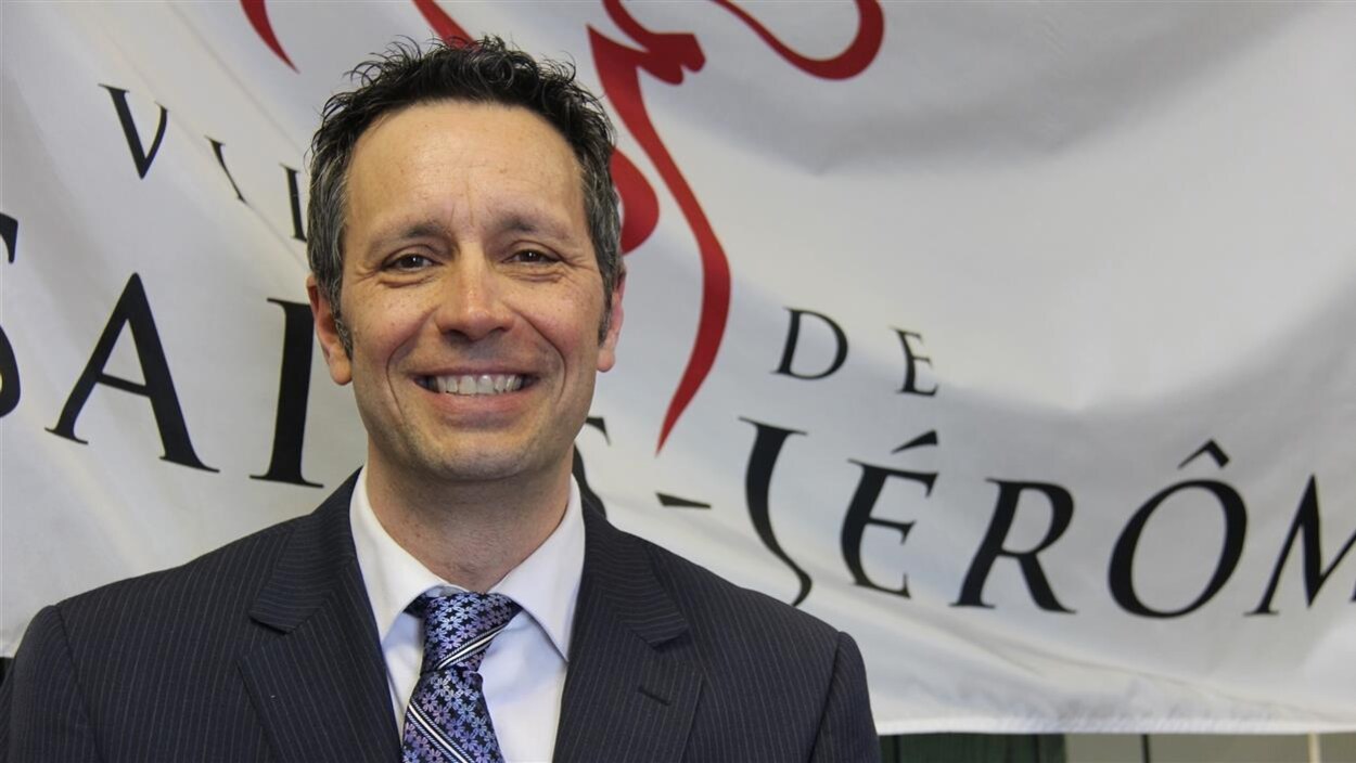 Plan rapproché du maire de Saint-Jérôme devant le drapeau de sa ville.