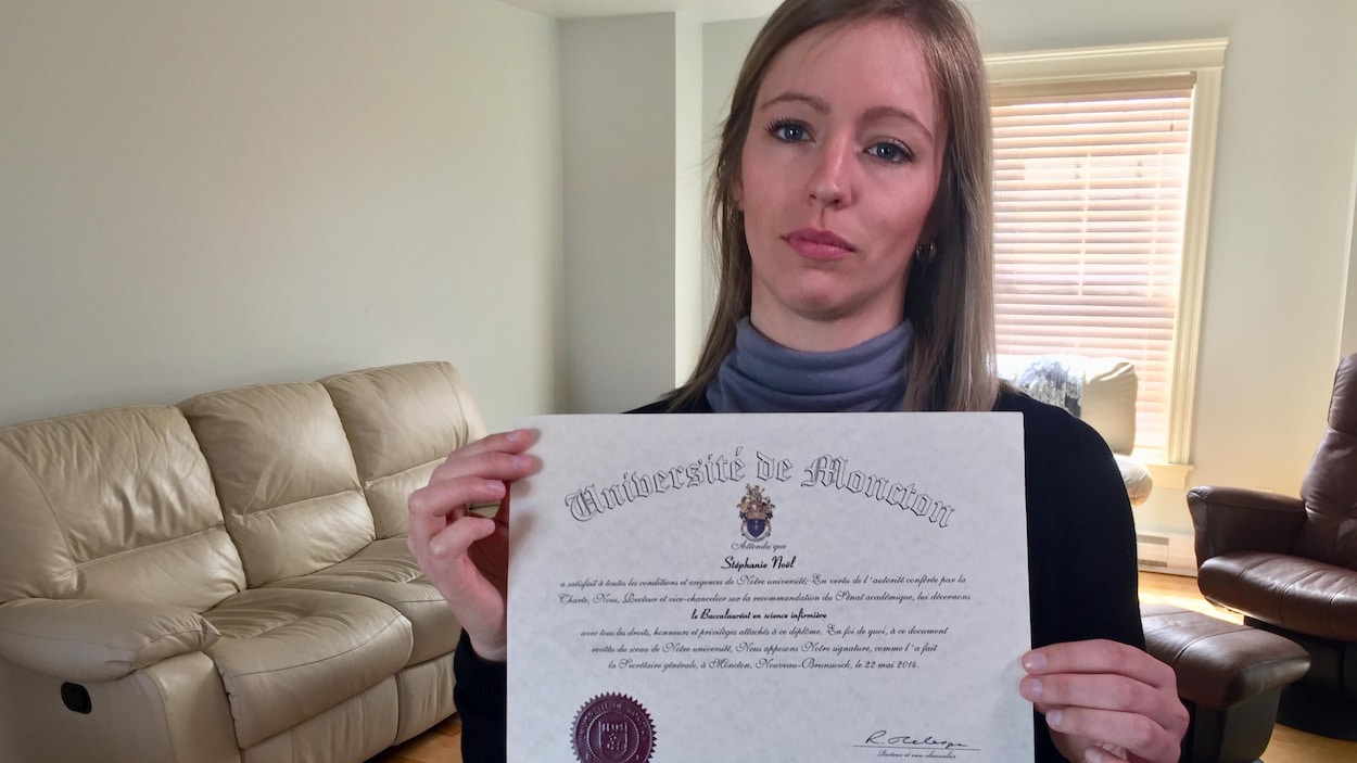 Une jeune femme triste qui tient son diplôme de sciences infirmières dans son salon. Une jeune femme triste qui tient son diplôme de sciences infirmières dans son salon.