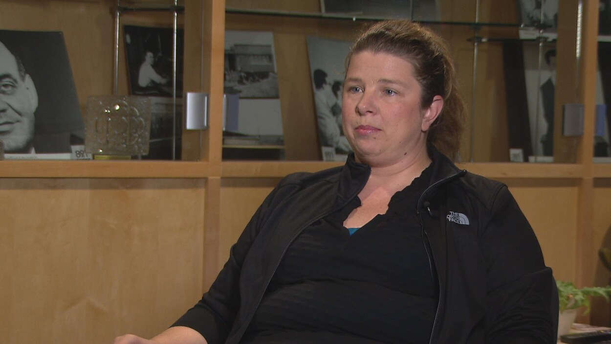 Elle est assise dans les studios de Radio-Canada pour une entrevue. Elle a les cheveux attachés et porte des vêtements noirs.