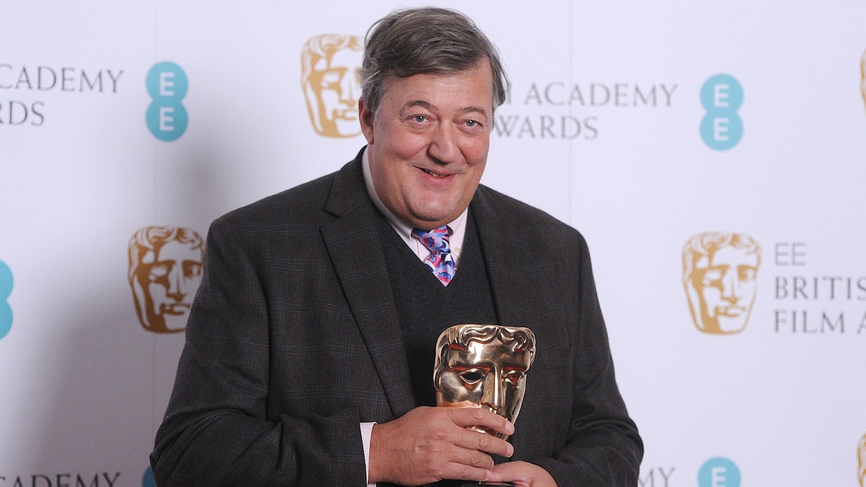 Stephen Fry tient une statuette des BAFTA Awards dans ses mains, souriant aux photographes Stephen Fry tient une statuette des BAFTA Awards dans ses mains, souriant aux photographes