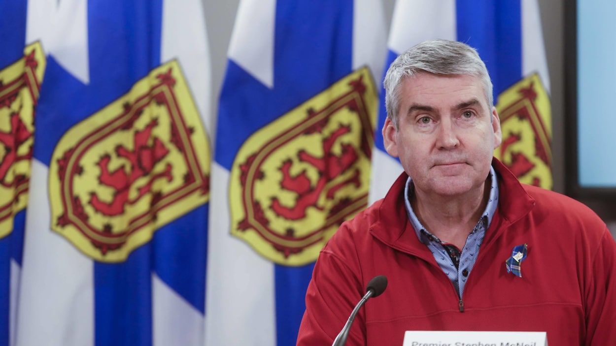 Stephen McNeil devant des drapeaux de la Nouvelle-Écosse.