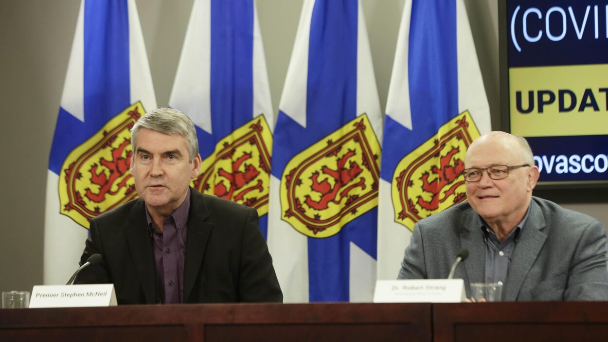 Deux hommes devant des drapeaux de la Nouvelle-Écosse.