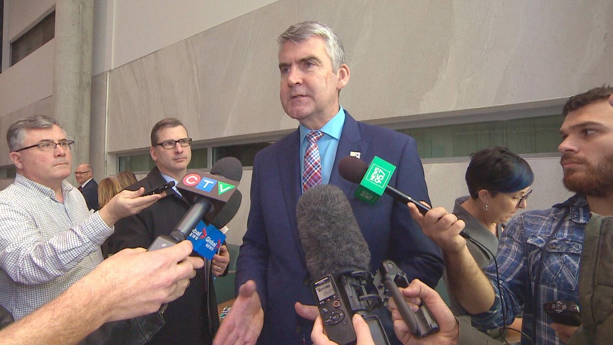 Stephen McNeil entouré de journalistes et de microphones.