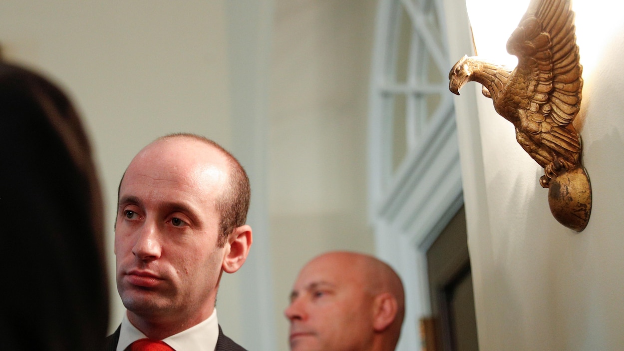 L'air dépité, Stephen Miller avance dans une pièce sous l’œil aiguisé de l'aigle américain, dont une statue est accrochée au mur.