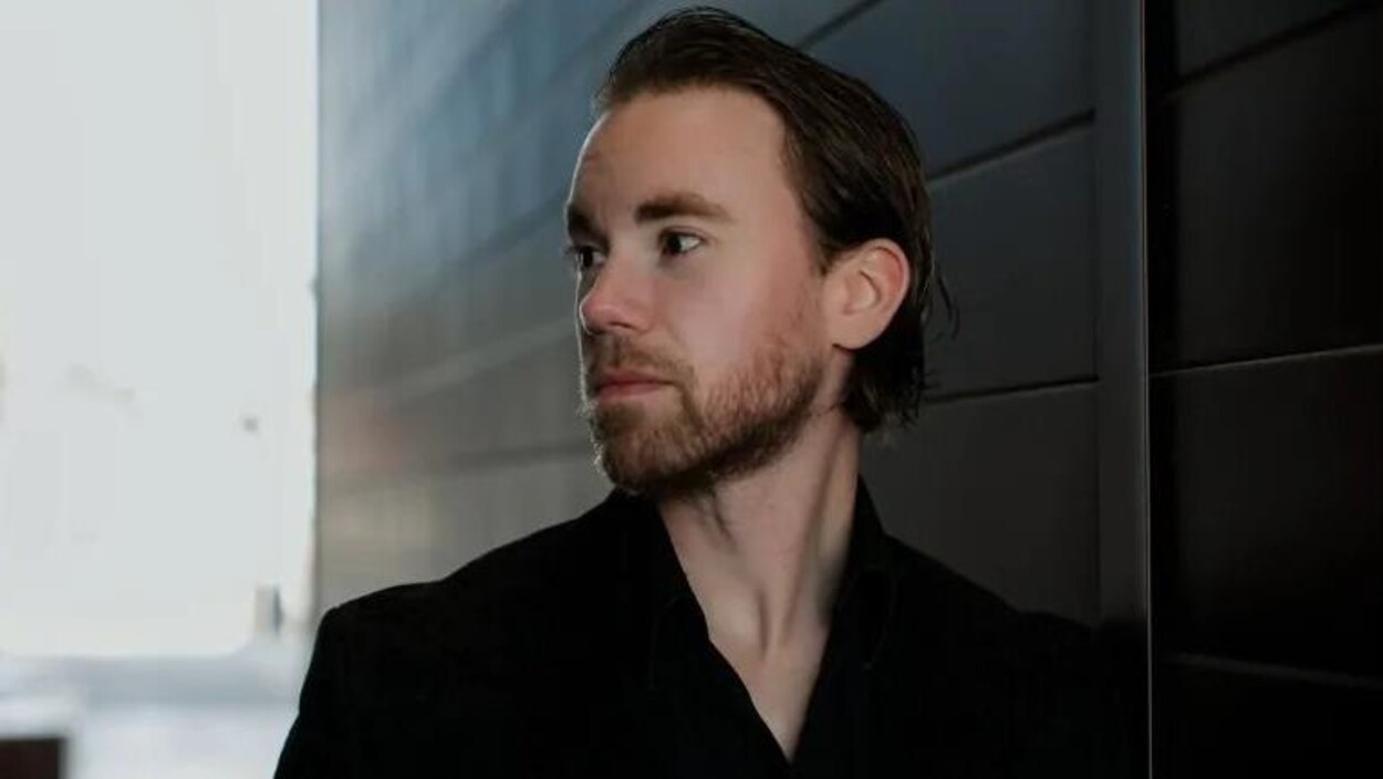 Adam Pottle à côté d'un mur, le regard tourné.