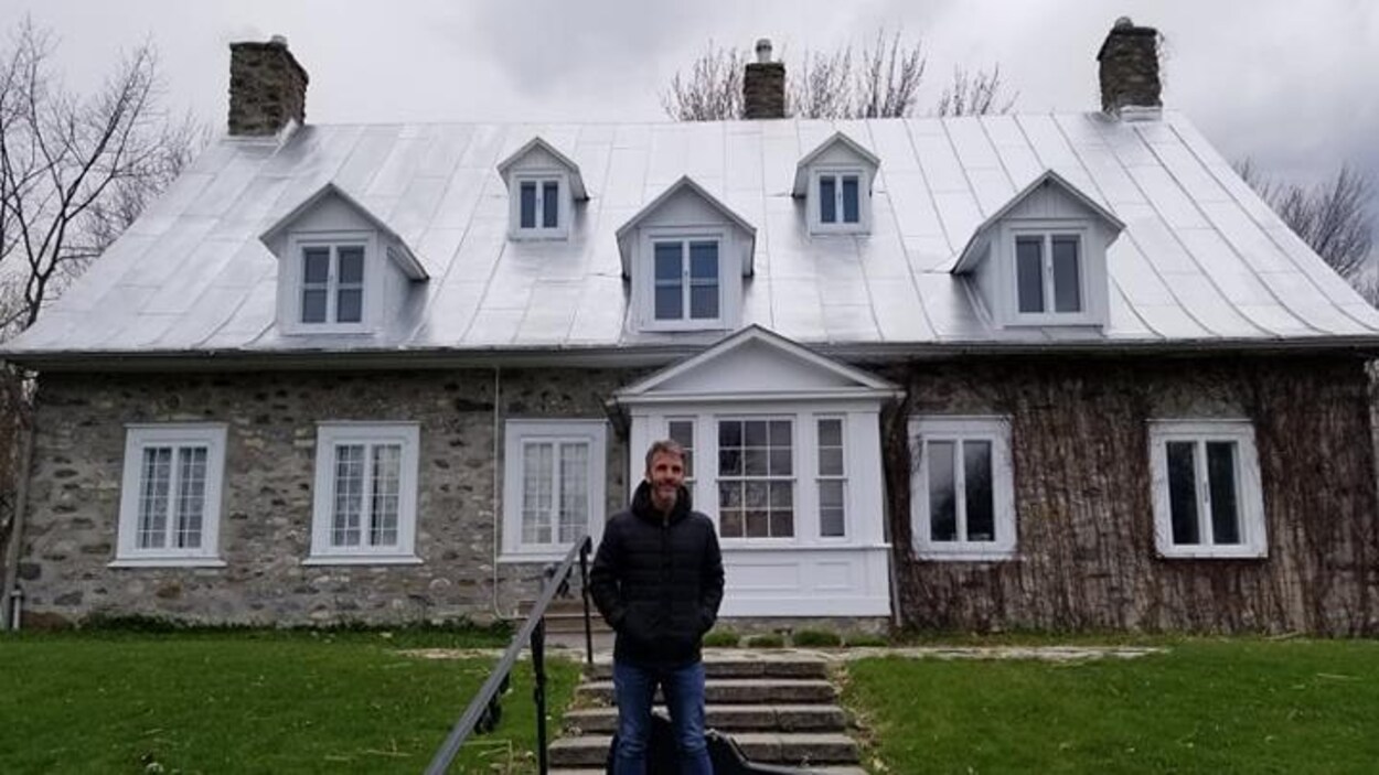 Un homme debout devant une vieille maison en pierres.