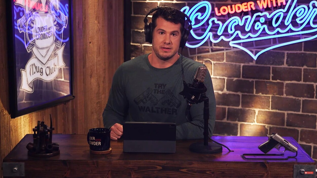 Une capture d'écran d'une vidéo dans laquelle on voit Steven Crowder en train de parler à la caméra. Il est assis à un bureau sur lequel sont déposés une tablette électronique, une tasse, des pipes, un microphone et un pistolet.