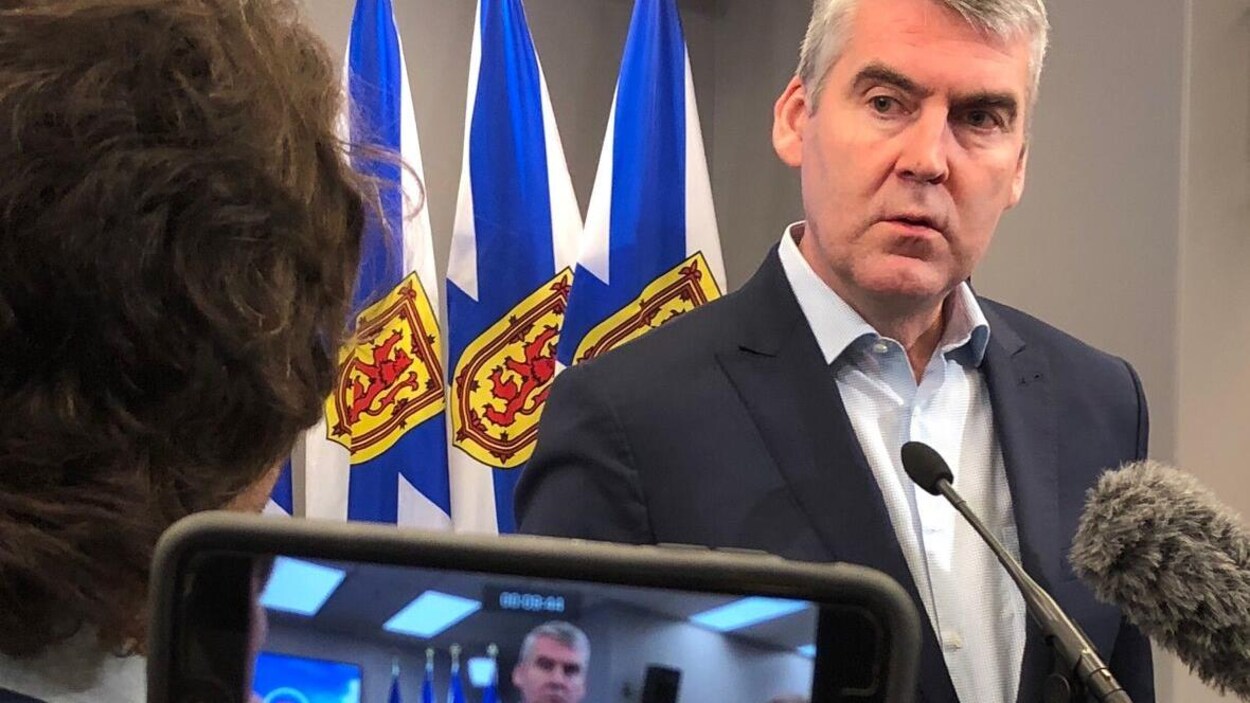 Stephen McNeil se tient devant des micros, des caméras et le drapeau de la Nouvelle-Écosse lors d'une conférence de presse.