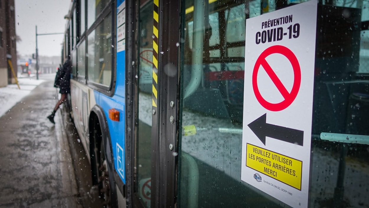 Une affiche sur laquelle il est écrit : prévention COVID-19, veuillez utiliser les portes arrière, merci