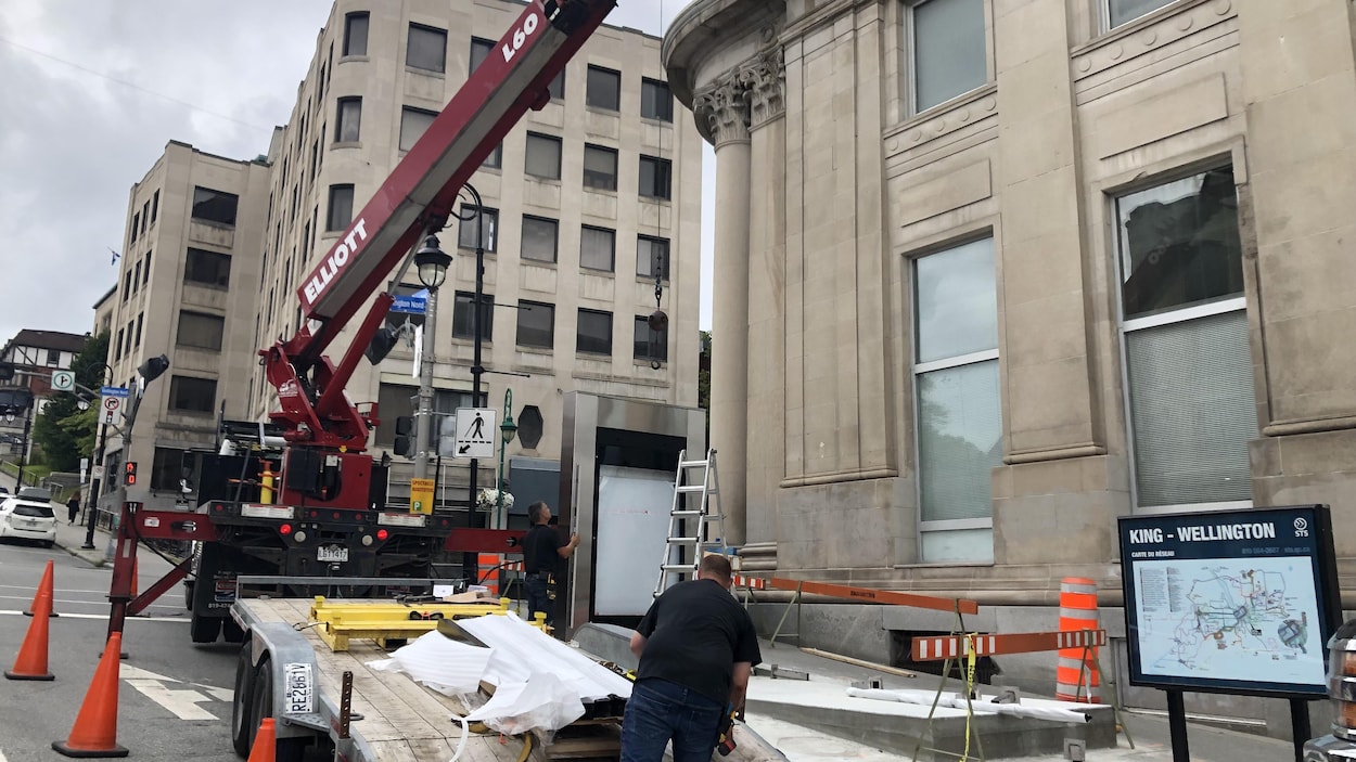 Des travailleurs s'affairent à l'installation d'un nouvel abribus à l'intersection King / Wellington, à Sherbrooke.