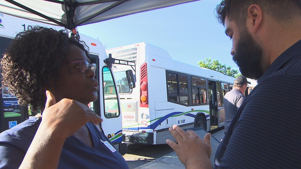 Femme parlant à une agente devant des autobus à la gare routière du centre-ville de Trois-Rivières.
