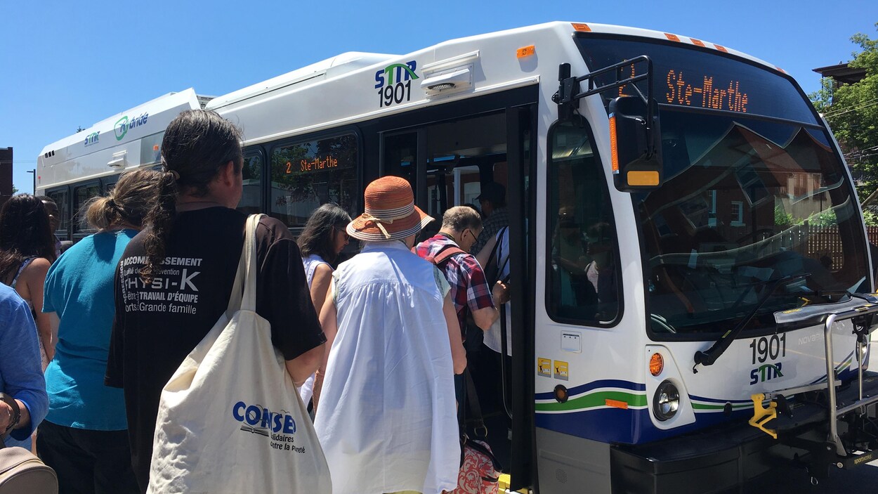 Des passagers en file d'indienne entrent dans un autobus.