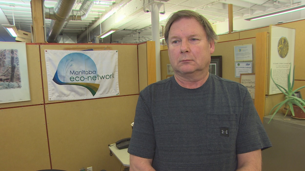 Un homme debout devant une affiche de Manitoba Éco-Network.