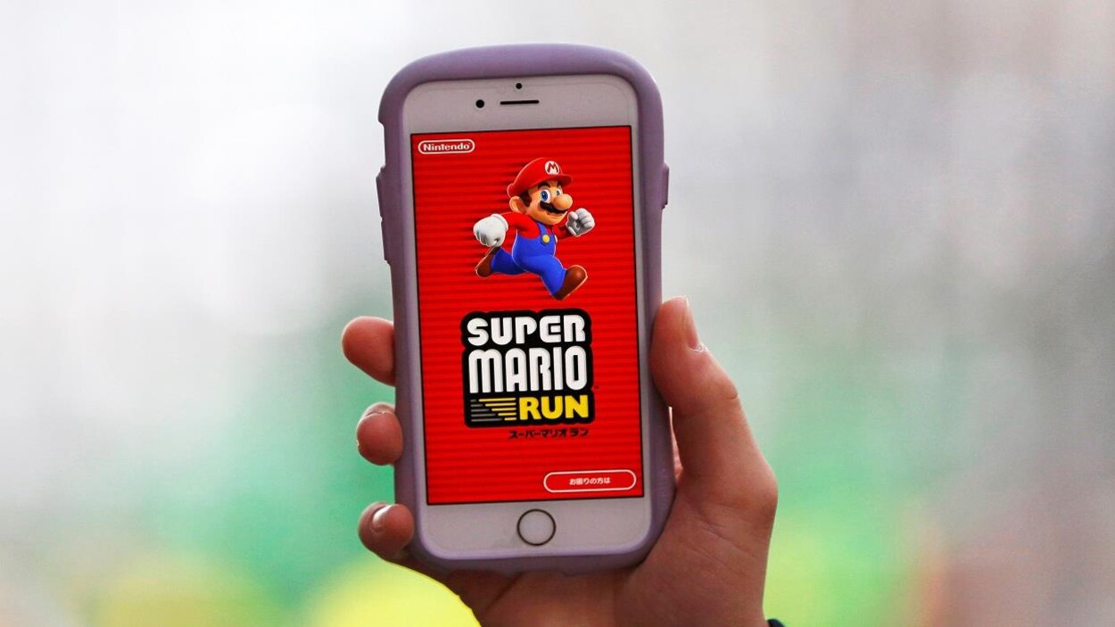 Une personne tient un téléphone cellulaire qui affiche une image du jeu Super Mario Run.