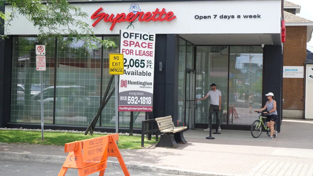 Deux personnes devant le magasin de cannabis Superette, situé dans le quartier Wellington Ouest d'Ottawa. Un panneau sur la rue indique que la rue est fermée et que seule la circulation locale y est permise.