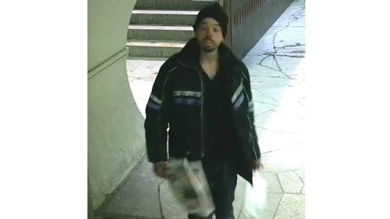 Un homme avec une tuque noire et un manteau noir avec des lignes blanches et violettes