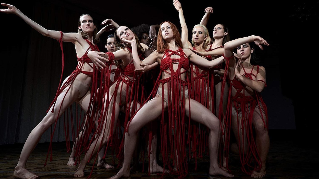 Des femmes vêtues de morceaux qui ressemblent à des cordes rouges sont regroupées pour une pose extraite d'un spectacle de danse. Des femmes vêtues de morceaux qui ressemblent à des cordes rouges sont regroupées pour une pose extraite d'un spectacle de danse.