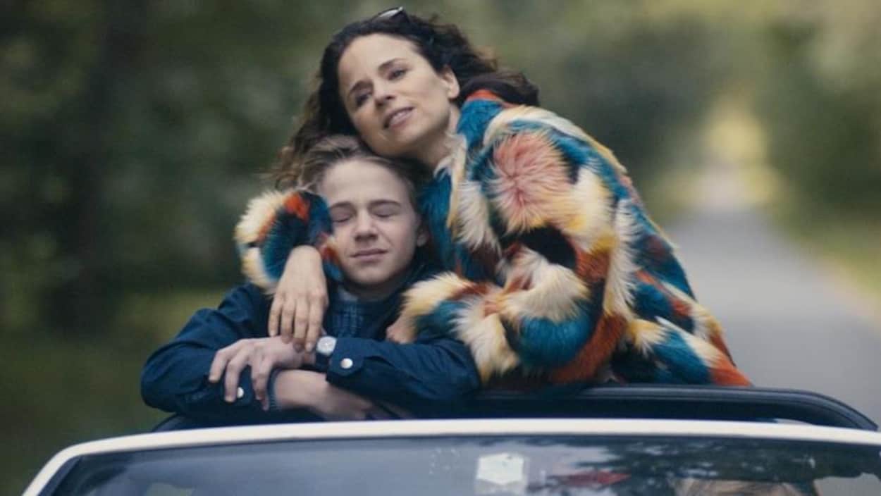 Une femme enlace un adolescent alors qu'ils sont debout dans une voiture. Une femme enlace un adolescent alors qu'ils sont debout dans une voiture.