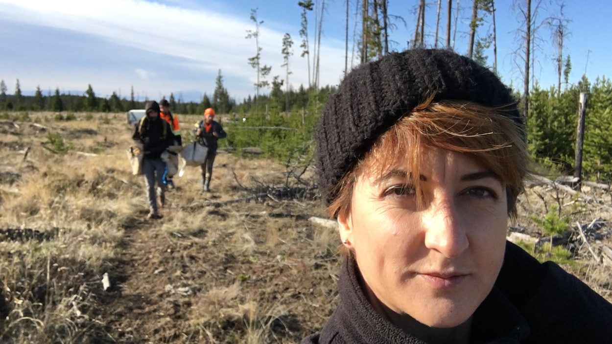 Suzie Gagnon avec ses trois coéquipiers en arrière-plan, dans un terrain à reboiser.