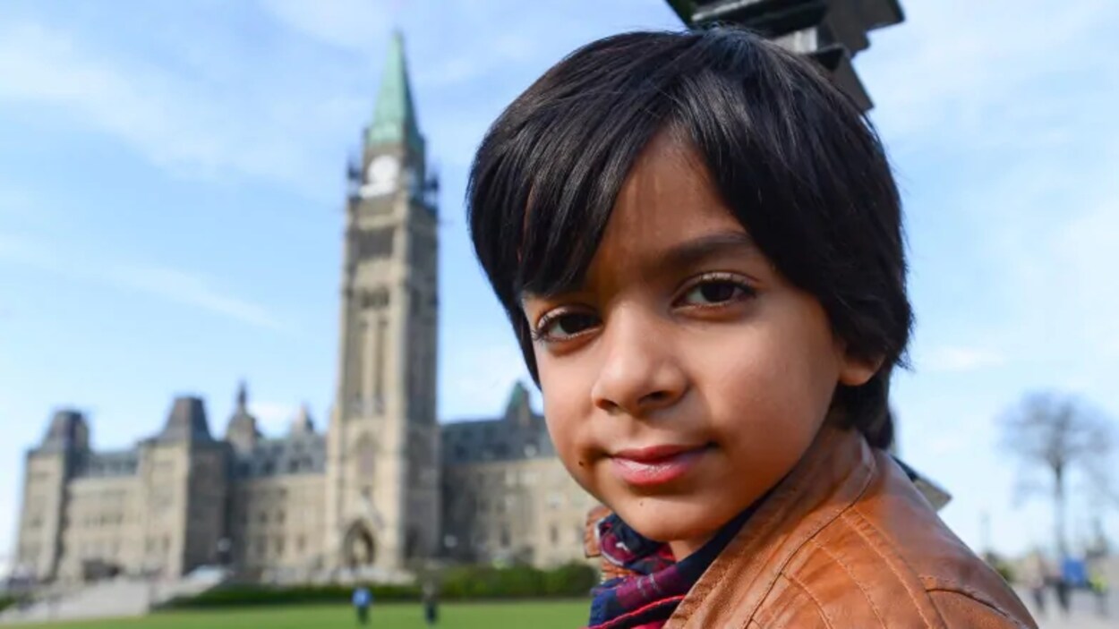 Syed Adam Ahmed regarde l'objectif. Derrière lui, le parlement.