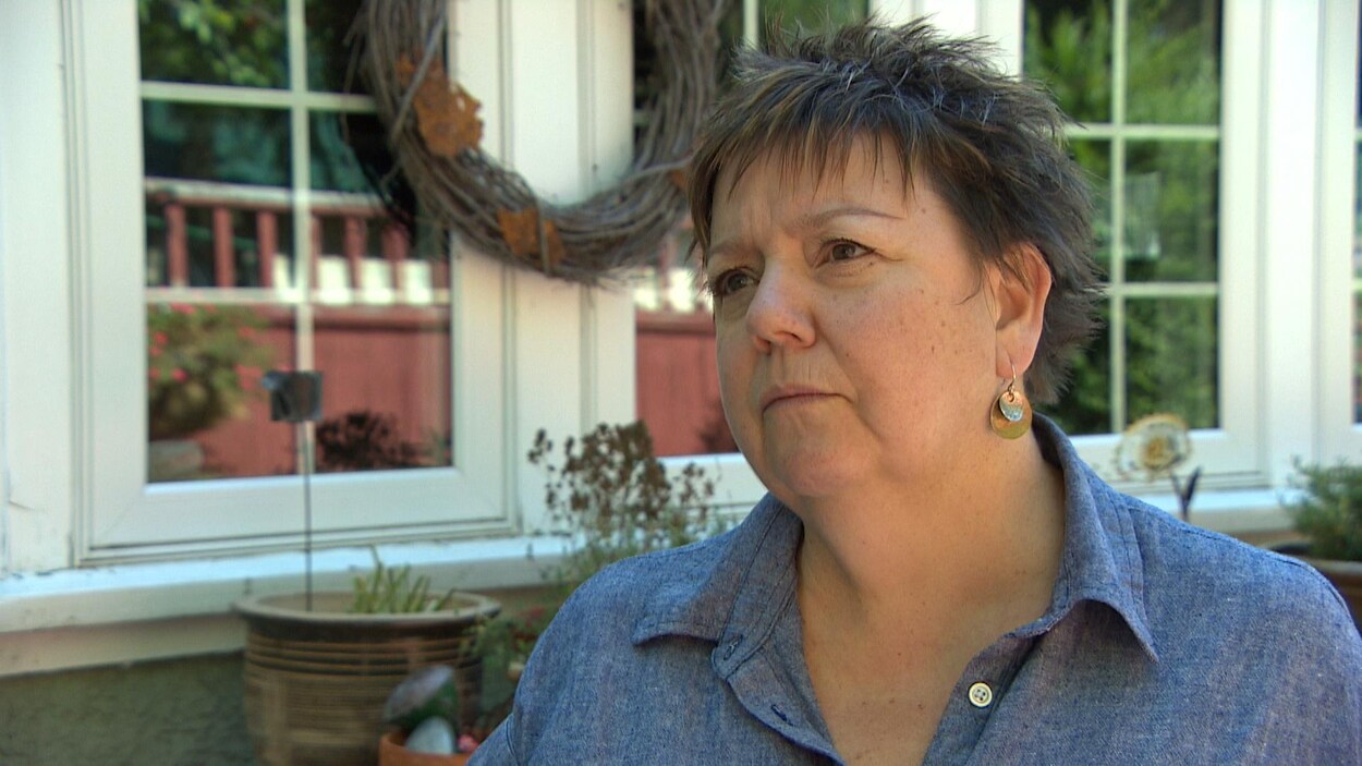 Sylvie Bergeron parle en entrevue devant la façade d'une maison.