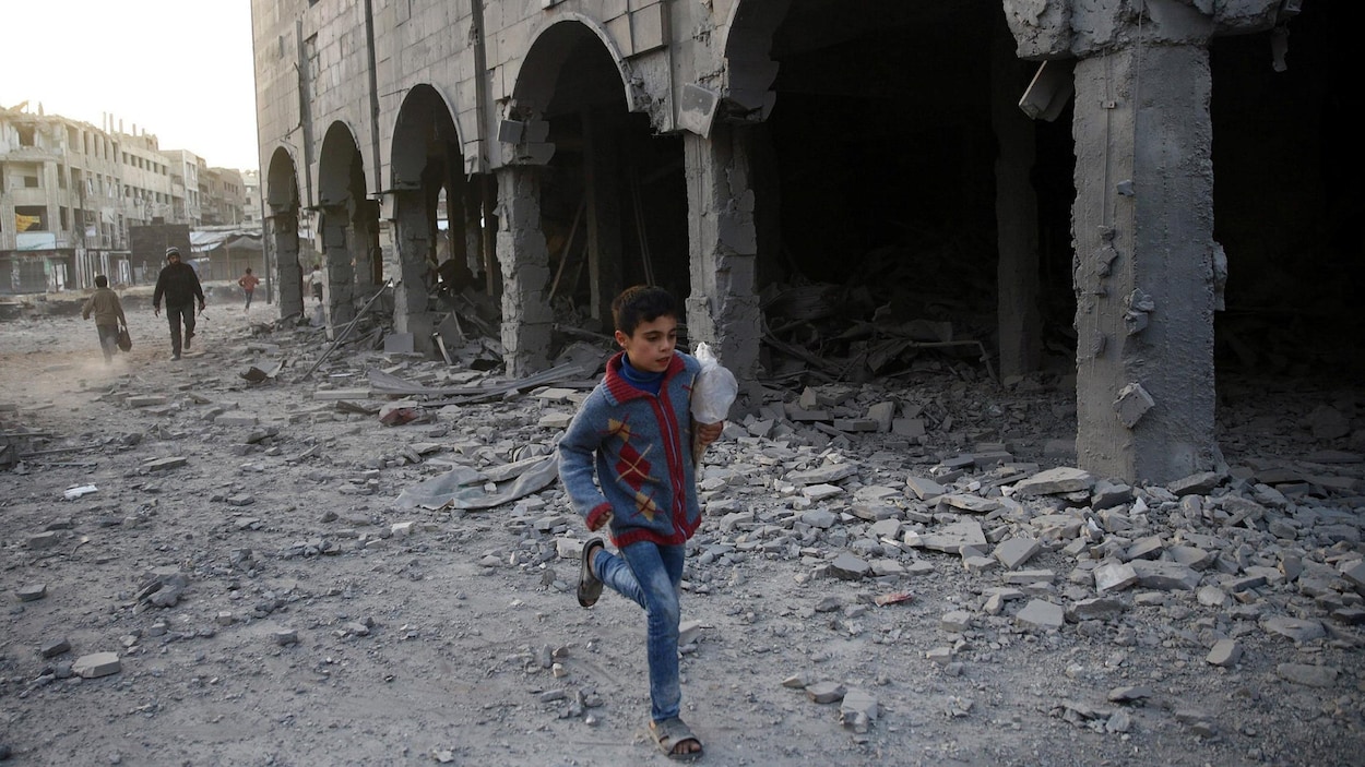Un garçon syrien court près d'un immeuble endommagé. Un garçon syrien court près d'un immeuble endommagé.