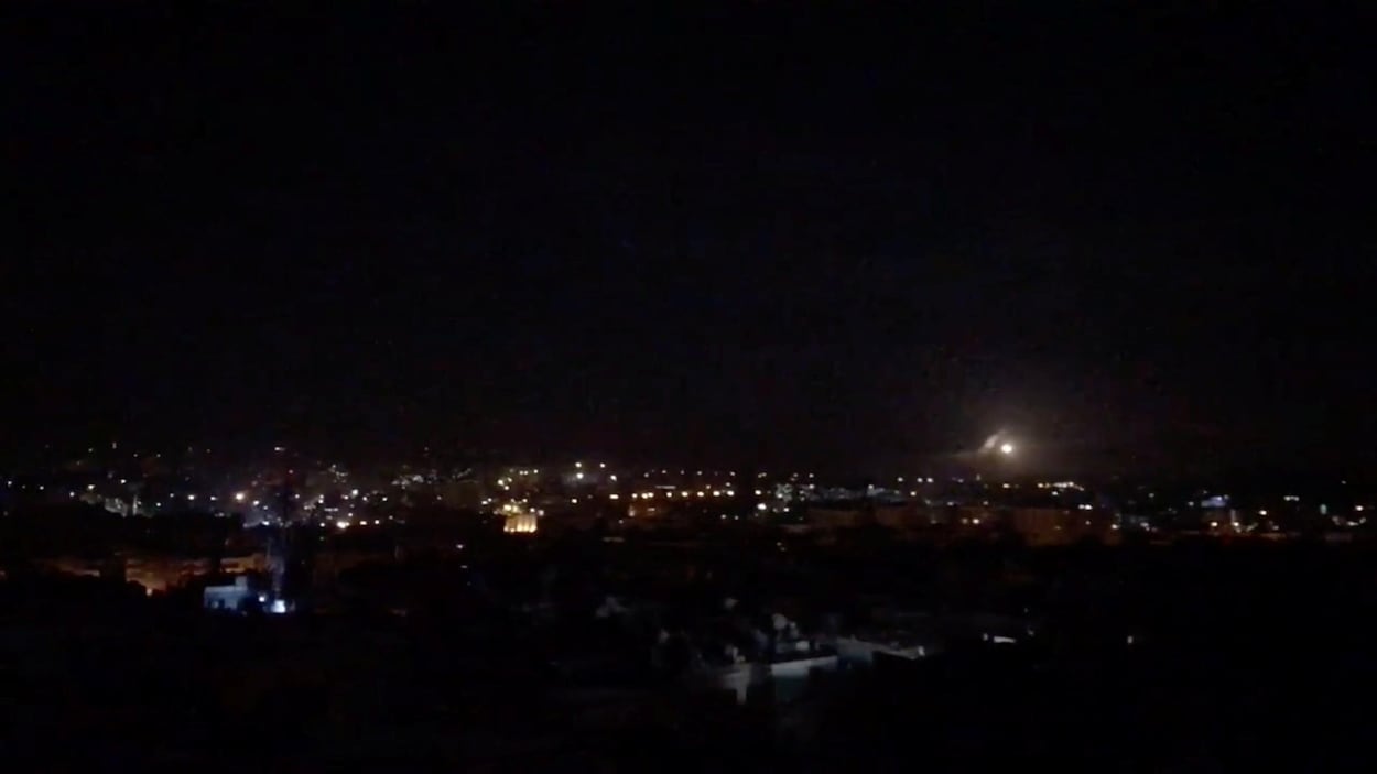 Une photo tirée d'une vidéo montre un point lumineux au loin dans la nuit sur une ville syrienne.
