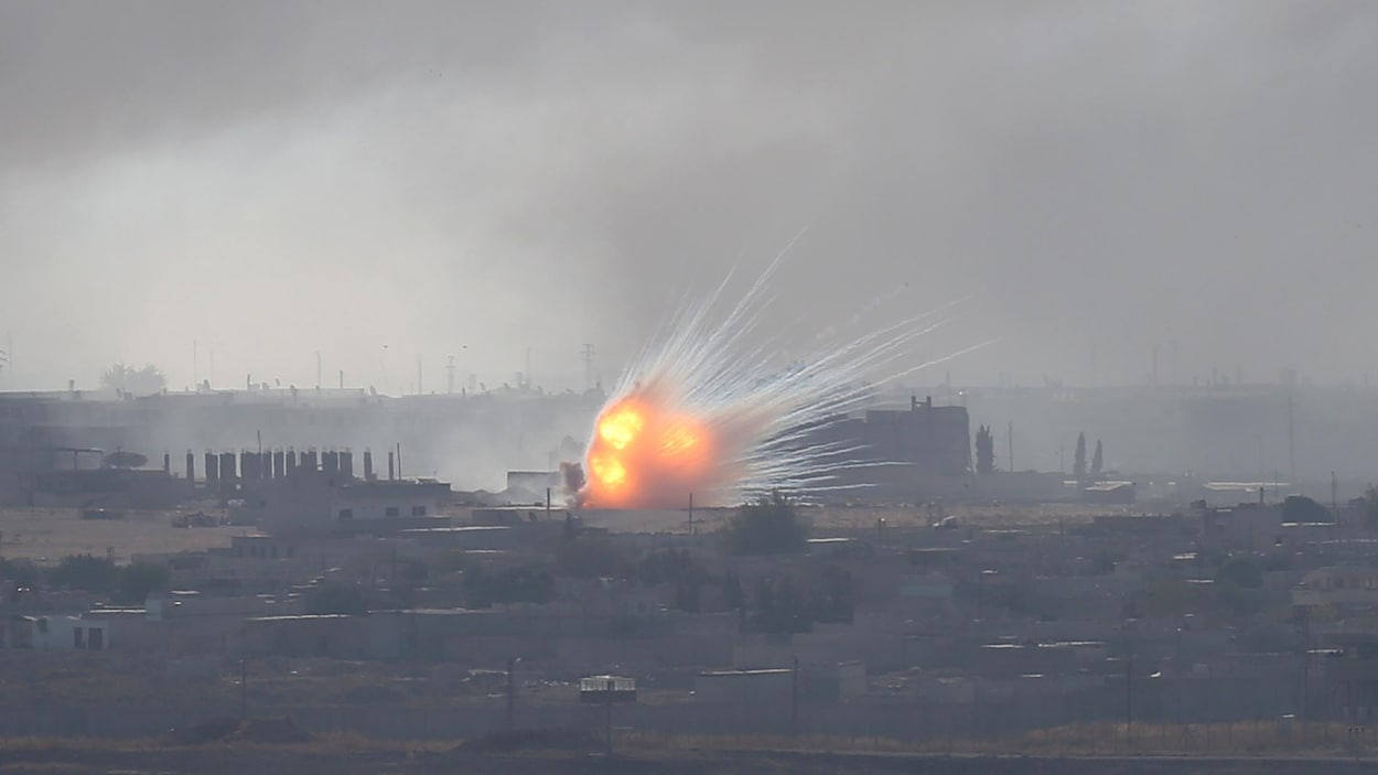 Feu et fumée d'une explosion près de bâtiments.