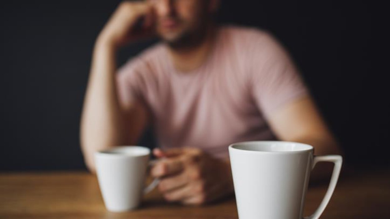 Un homme devant une tasse posée sur une table.